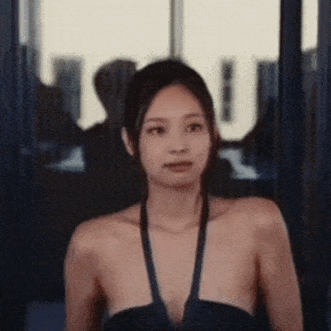 a woman in a swimsuit is standing in front of a window and looking at the camera .