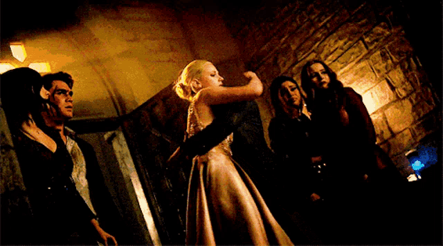 a group of people are standing around a woman in a long dress