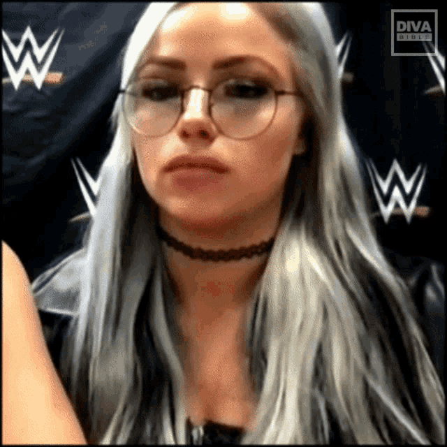 a woman wearing glasses and a choker is standing in front of a sign that says diva