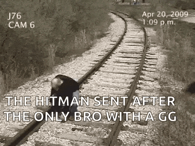 a man is kneeling on train tracks with a gun in his hand .