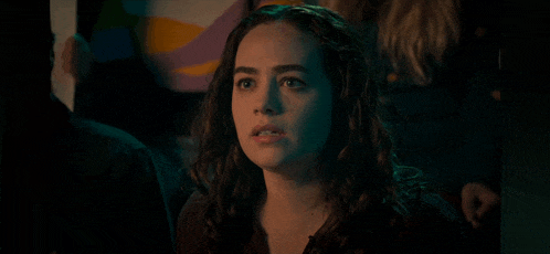 a woman is sitting in a dark room with a green light behind her