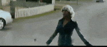 a woman in a black jacket is walking down a street .