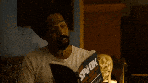 a man in a white shirt is reading a book called x-book