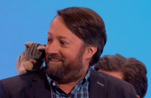 a man with a beard is holding a stuffed animal on his shoulder