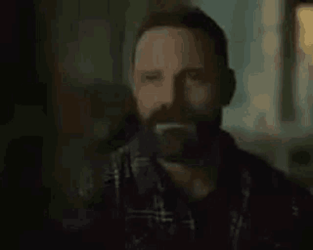 a man with a beard is wearing a plaid shirt .