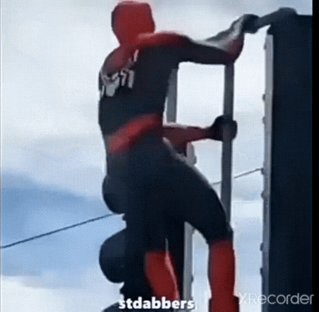 a man in a spiderman costume is climbing a ladder .