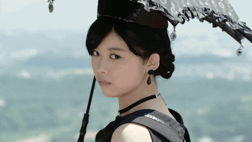 a woman with an umbrella on her head looks at the camera
