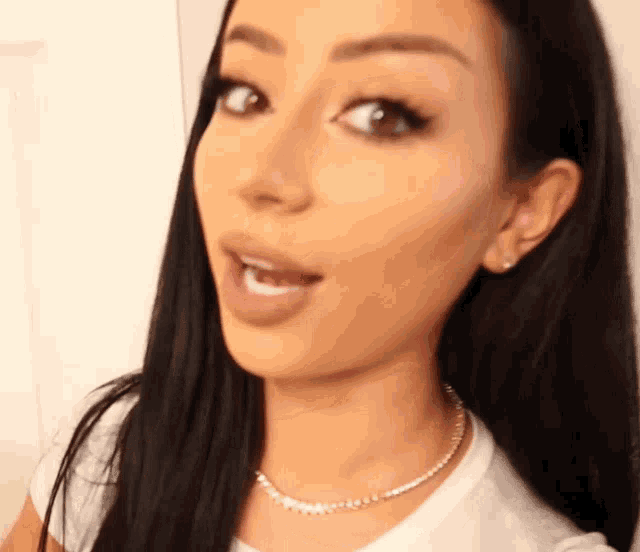 a woman wearing a white shirt and a necklace with diamonds