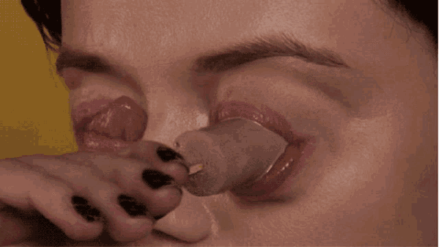 a close up of a woman eating a popsicle with her tongue out