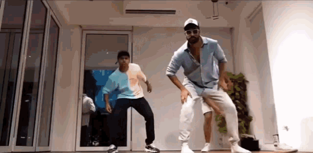 two men are dancing together in a room in front of a glass door .