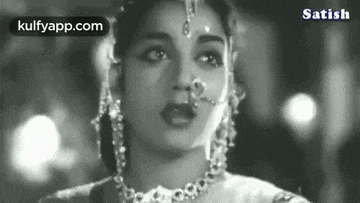 a black and white photo of a woman wearing a nose ring and necklace .