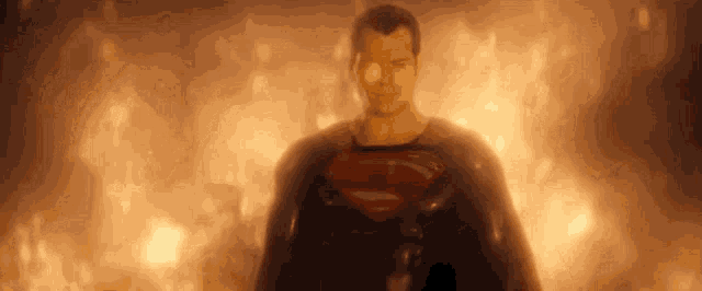 superman is standing in front of a fire and looking at the camera .