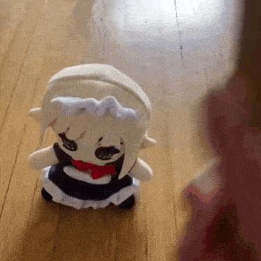 a stuffed doll in a maid outfit is sitting on a wood floor