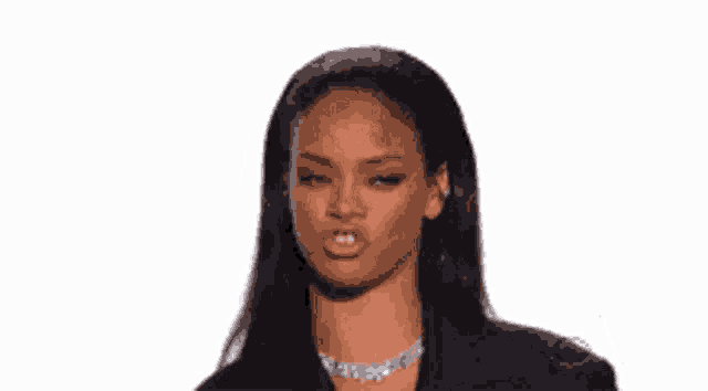 a woman wearing a necklace and a black jacket is making a funny face .