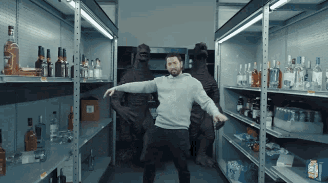 a man in a grey sweatshirt is dancing in a store surrounded by empty shelves