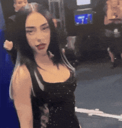 a woman in a black dress is standing in front of a group of people .