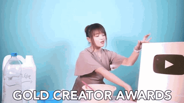 a woman is standing in front of a sign that says gold creator awards on it