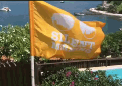 a yellow flag that says silent morning is flying in front of a body of water