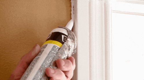 a person is applying caulk to a window