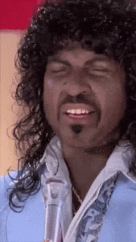a man with curly hair and a moustache is smiling with his eyes closed