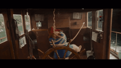a bear in a red hat is steering a ship
