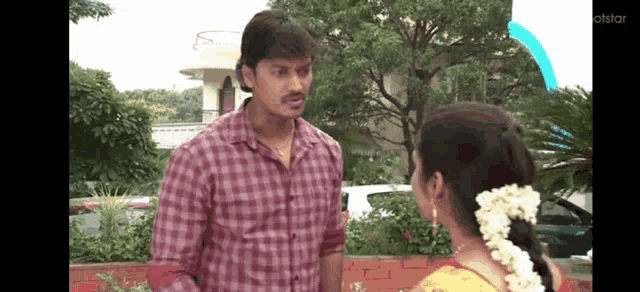 a man in a plaid shirt is talking to a woman in a yellow saree