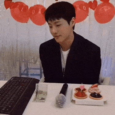 a man is sitting at a desk with a keyboard and a microphone and a stack of money that says 10000 on it