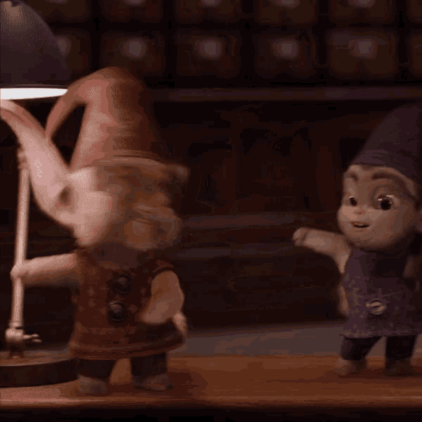 two stuffed gnomes are standing next to each other on a wooden table