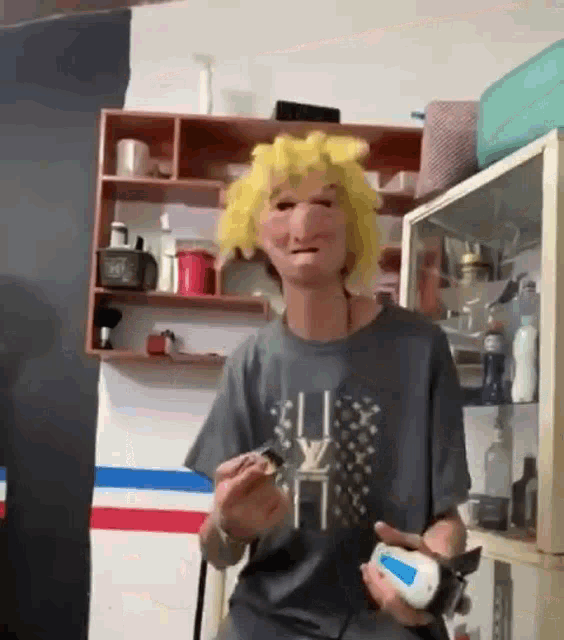 a man wearing a mask and a wig is holding a remote control in a room .
