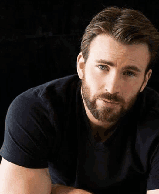 a man with a beard wearing a black shirt looks at the camera