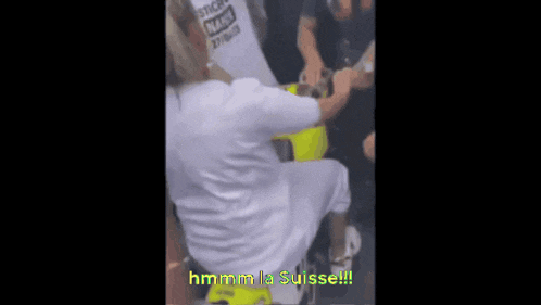 a woman in a white shirt is dancing in front of a crowd with the words hmm la suisse written on the bottom