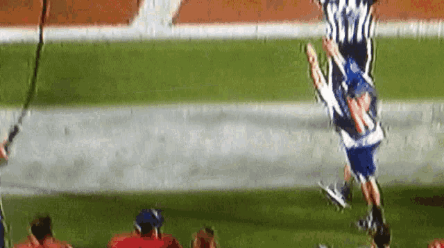 a football referee is jumping in the air while a player tries to catch the ball