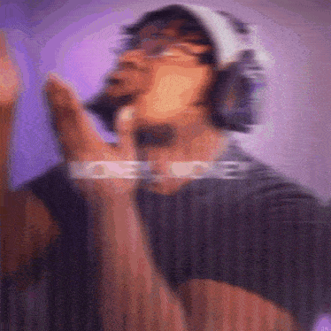 a blurry picture of a man wearing headphones and giving a peace sign .