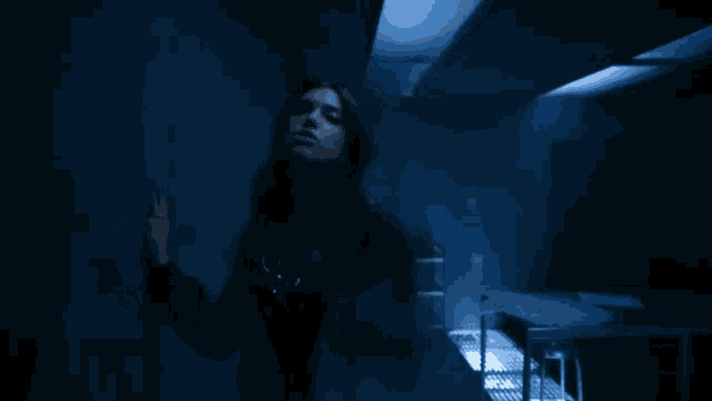 a woman is standing in a dark room with blue lights