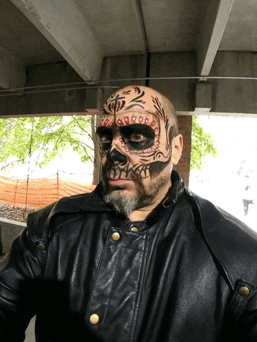 a man in a black leather jacket has face paint on