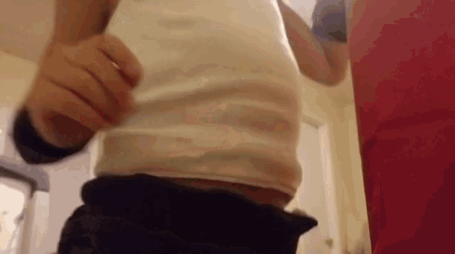 a person wearing a white tank top and black shorts is standing in a bathroom .