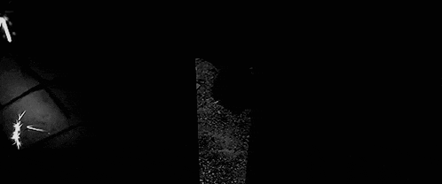 a black and white photo of a person standing in the dark with a gun .