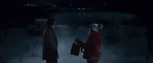 a man and a woman are walking in the snow holding hands .