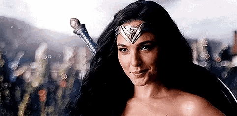 a woman in a wonder woman costume is smiling and holding a sword in her hand .