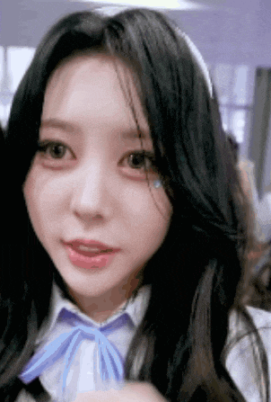 a close up of a girl with long black hair wearing a white shirt and a purple bow tie .
