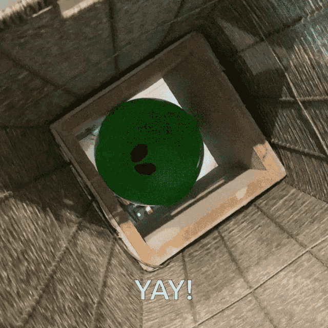 a green bowling ball in a box with the words yay written below it