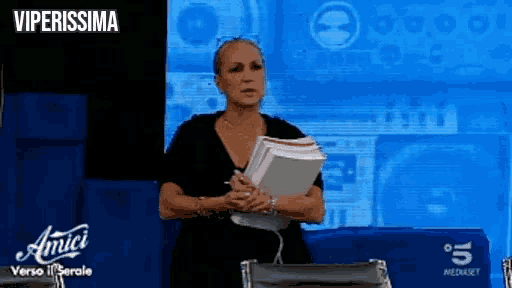 a woman sitting in front of a screen that says amici on it