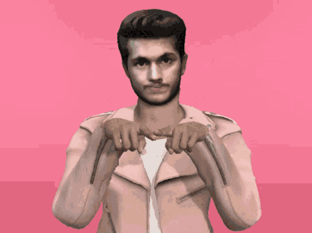 a man wearing a pink jacket is making a peace sign