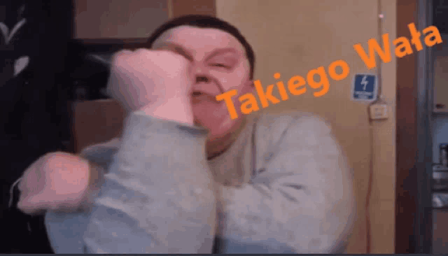 a man holds his fist up in front of a sign that says takiego wala