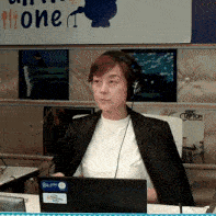a woman wearing headphones is sitting in front of a sign that says " one "