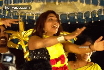 a woman in a yellow dress is dancing with her arms outstretched in front of a crowd .