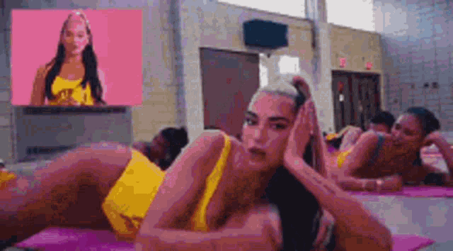 a woman in a yellow swimsuit is laying on a pink yoga mat .