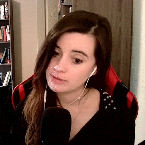 a woman wearing headphones and a black shirt is sitting in a chair in front of a microphone .