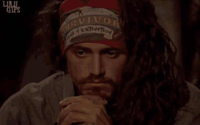 a man with long hair wearing a survivor bandana on his head
