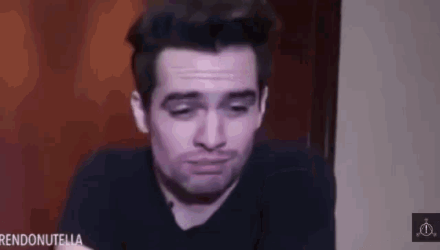 a man in a black shirt is making a funny face with his eyes closed .